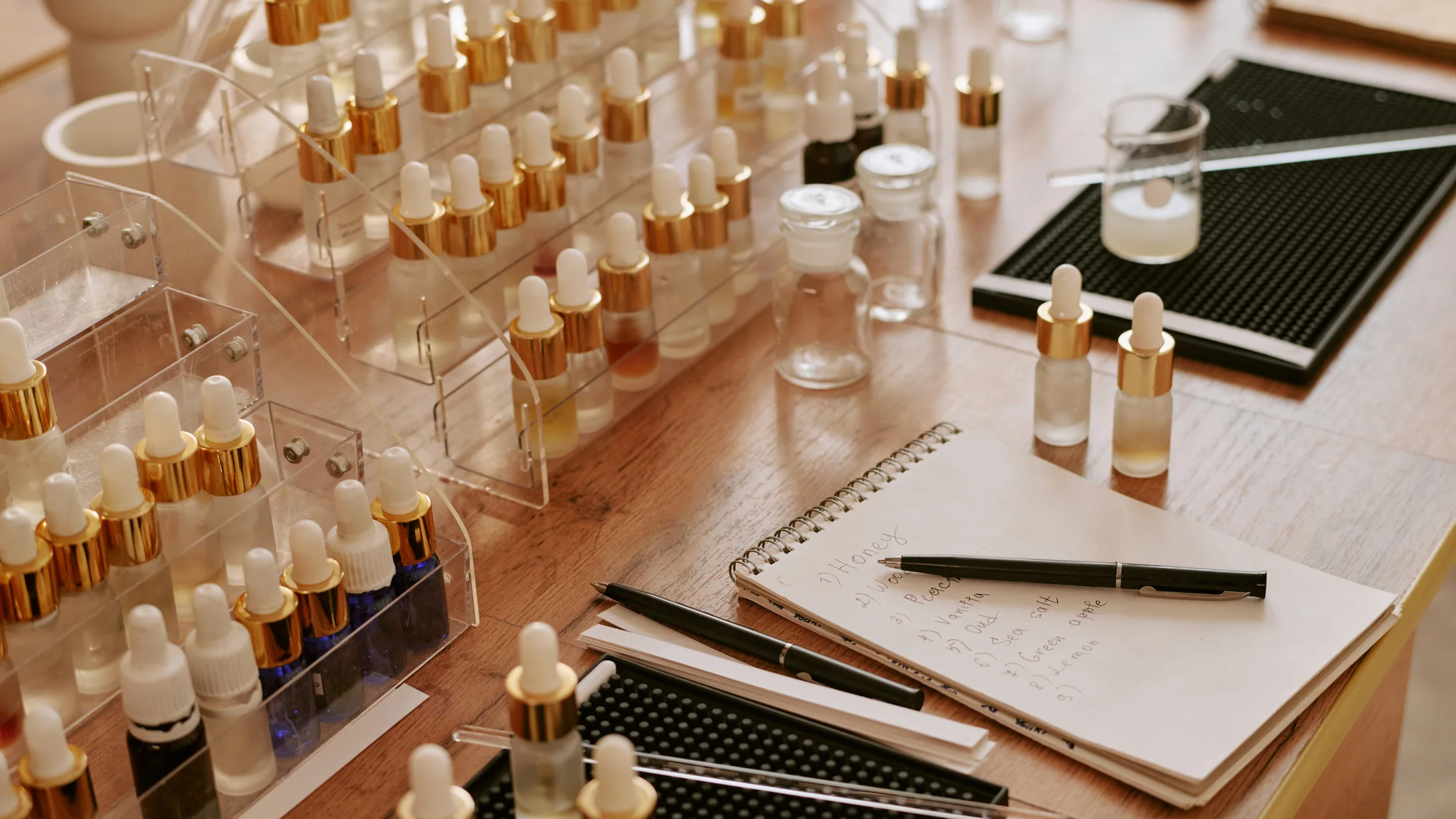 Product samples and glass dropper bottles arranged beside a notebook on a worktable.