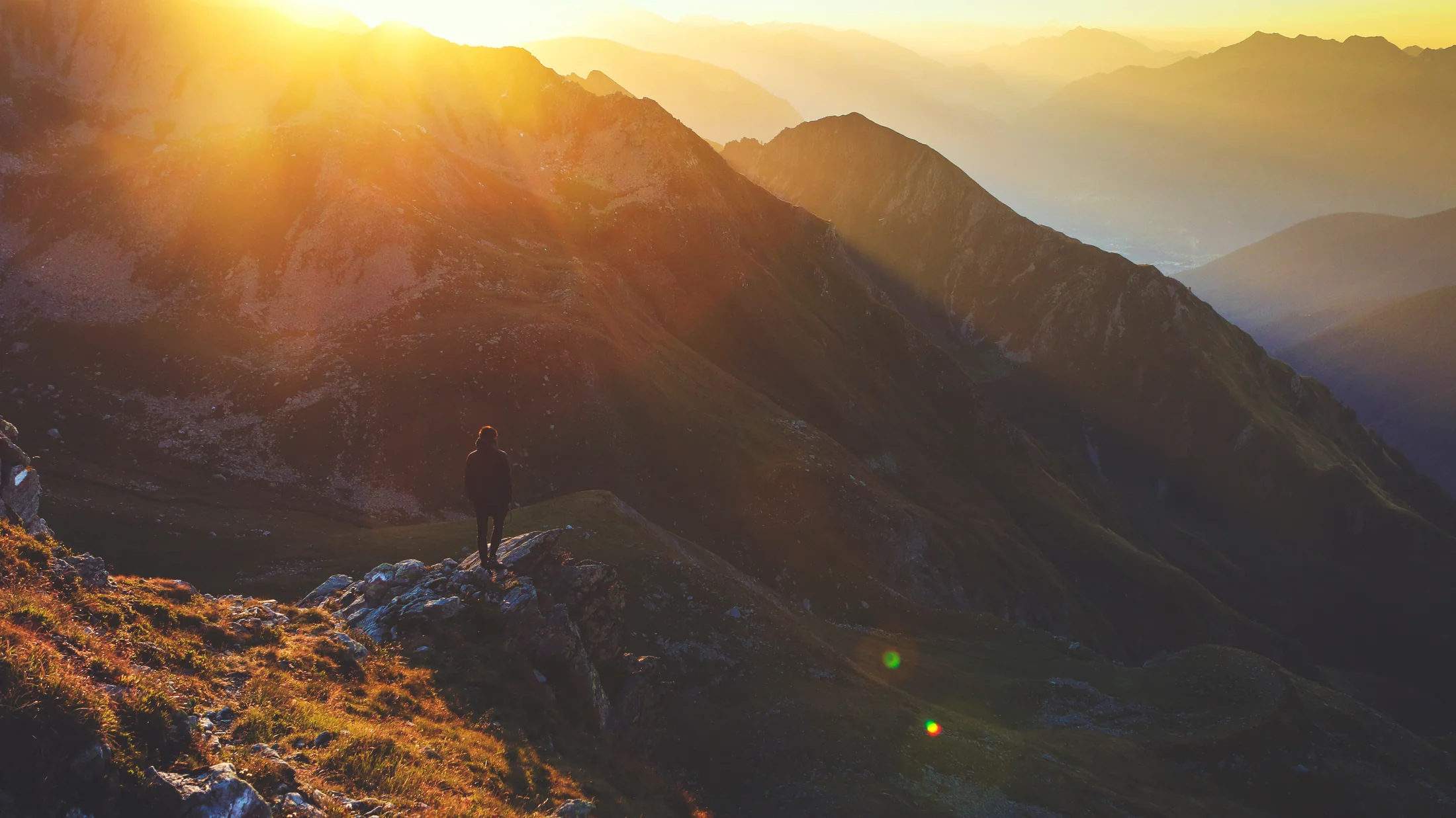 Sunlight reaching across a series of mountain ridges