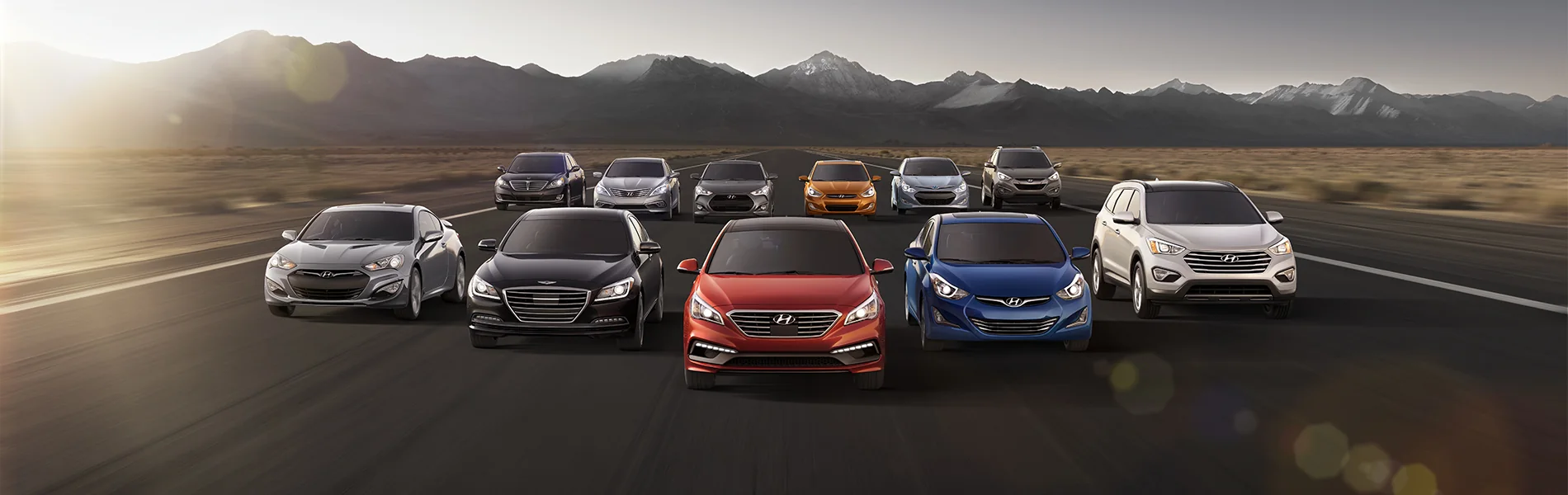 A lineup of passenger vehicles on an open road with mountains behind them