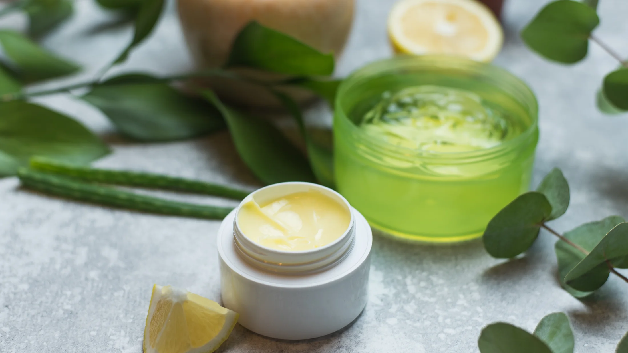 Skincare cream jars with aloe and citrus in a natural light composition.